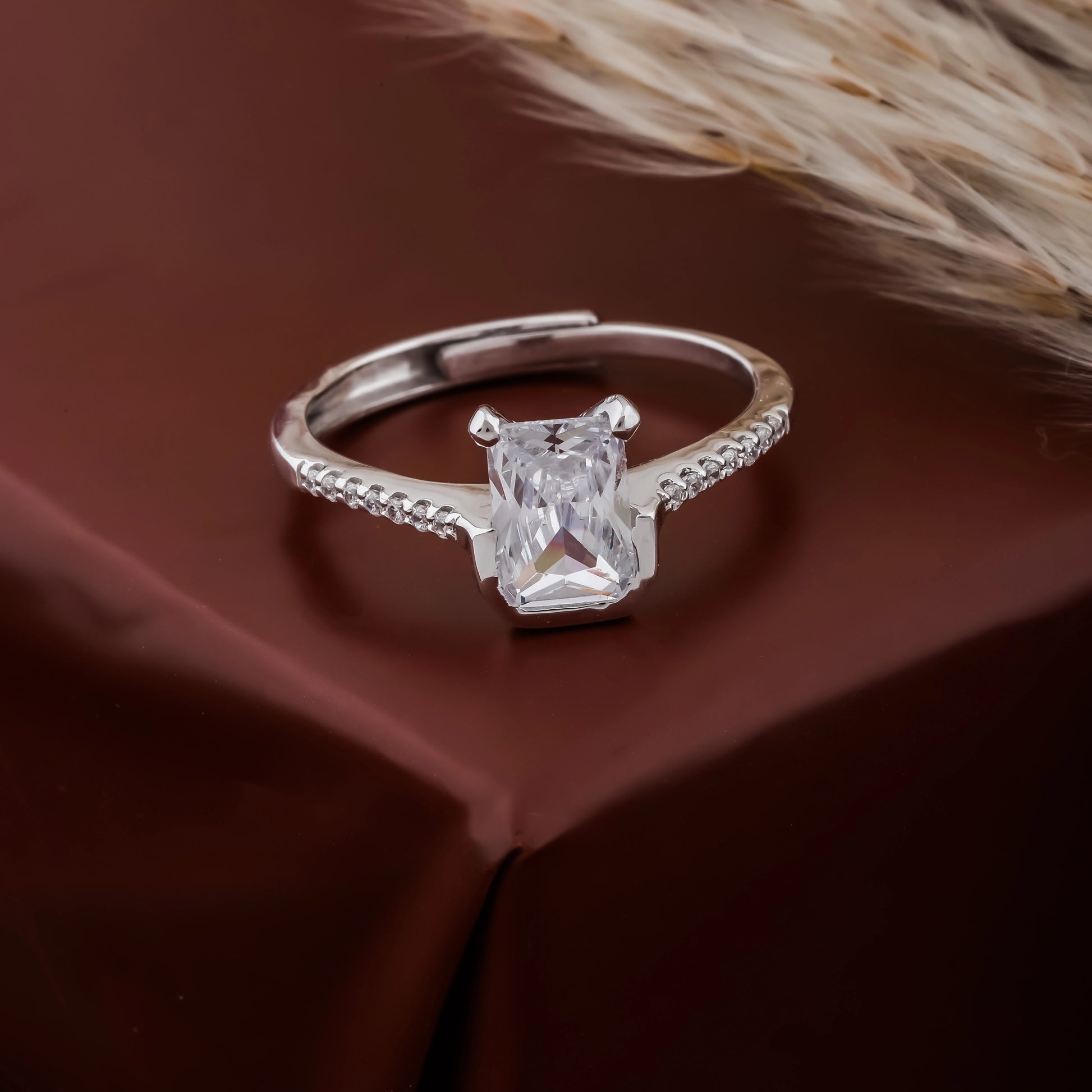 Silver ring with a large diamond on a brown fabric background