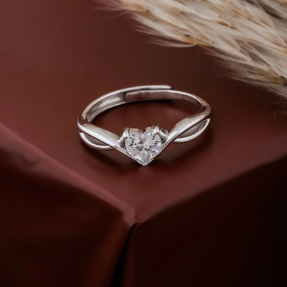 Silver ring with a heart-shaped diamond on a brown fabric background