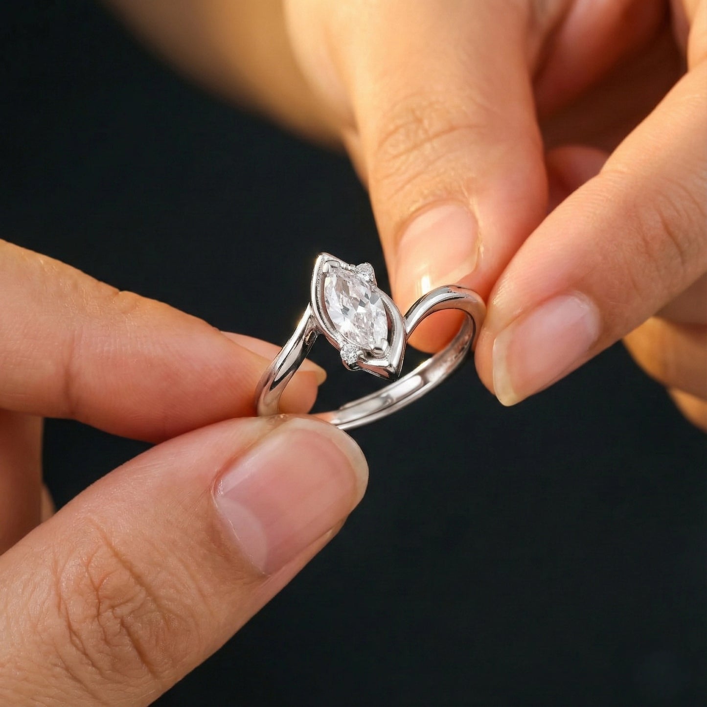 Close-up of hands holding a silver ring with a diamond