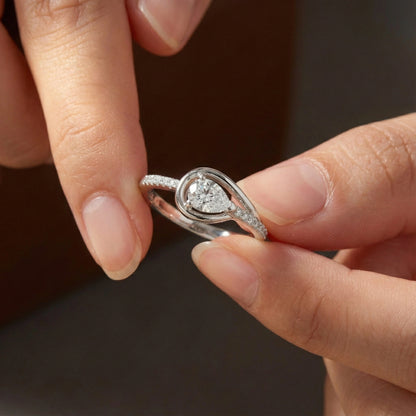 Close-up of a hand holding a silver ring with a diamond on a dark background