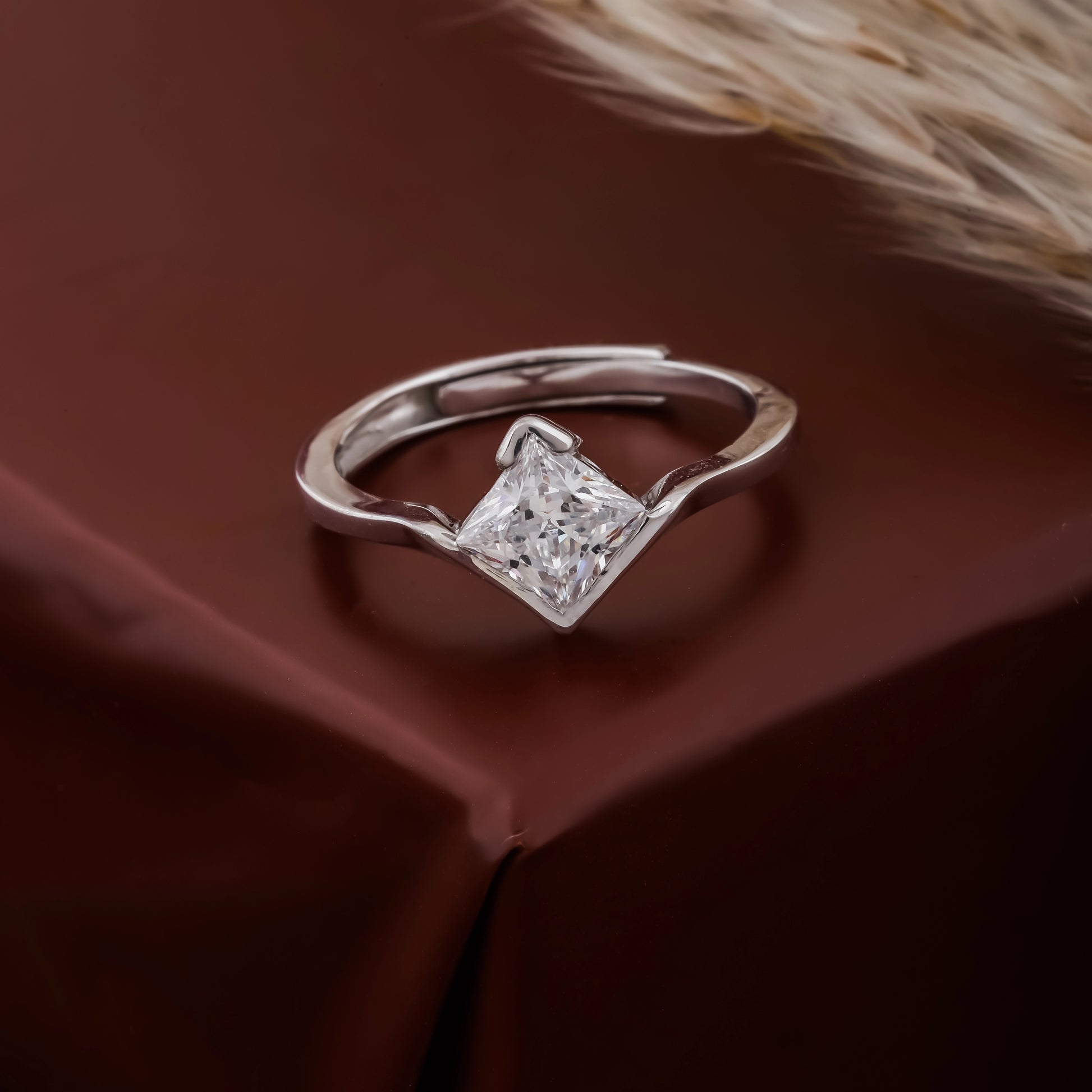 Silver ring with a diamond on a brown fabric background
