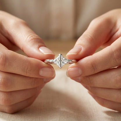 Close-up of hands holding a silver ring with a diamond-shaped design.