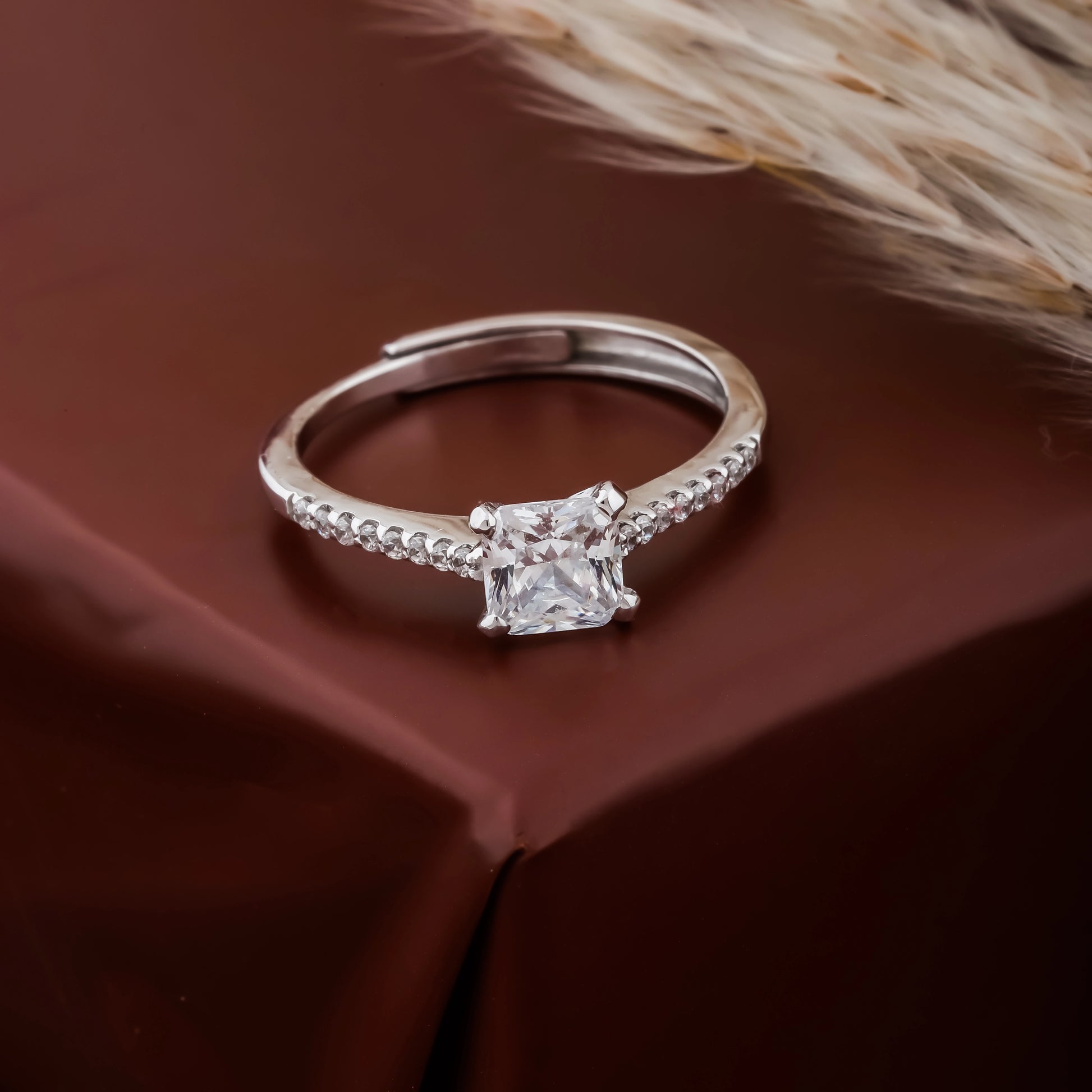 Silver ring with a diamond on a brown fabric background
