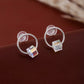 Silver hoop earrings with colorful square charms on a brown surface