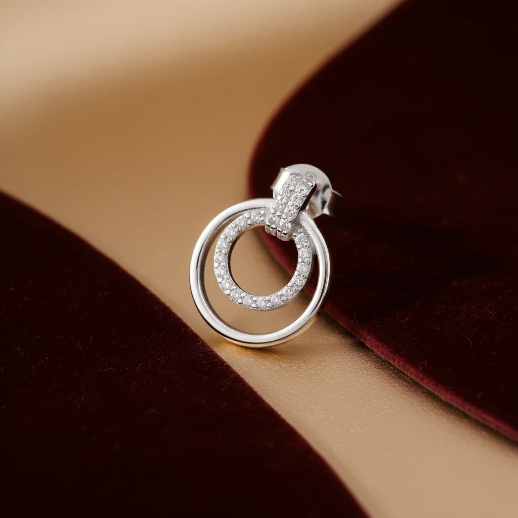 Silver earring with two interlocking rings on a brown surface