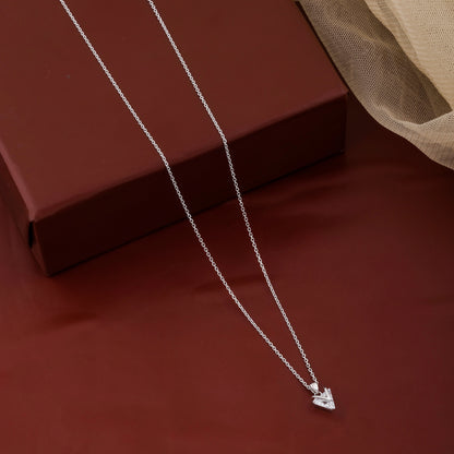 Silver necklace with a heart pendant on a red surface