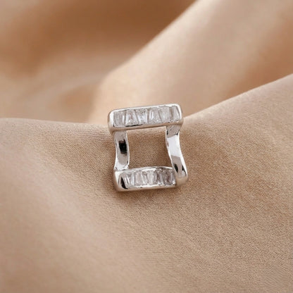 Silver earring with rectangular gemstones on a beige fabric background