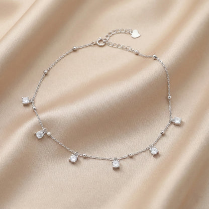 Silver bracelet with heart charm on a beige fabric background