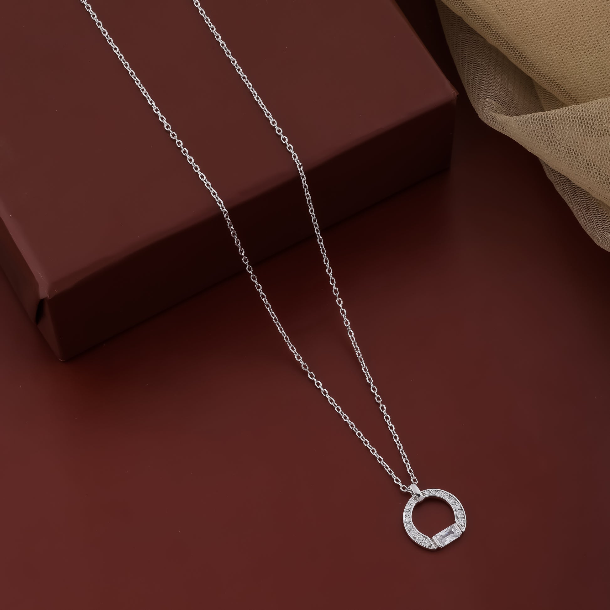 Silver necklace with a circular pendant on a brown surface