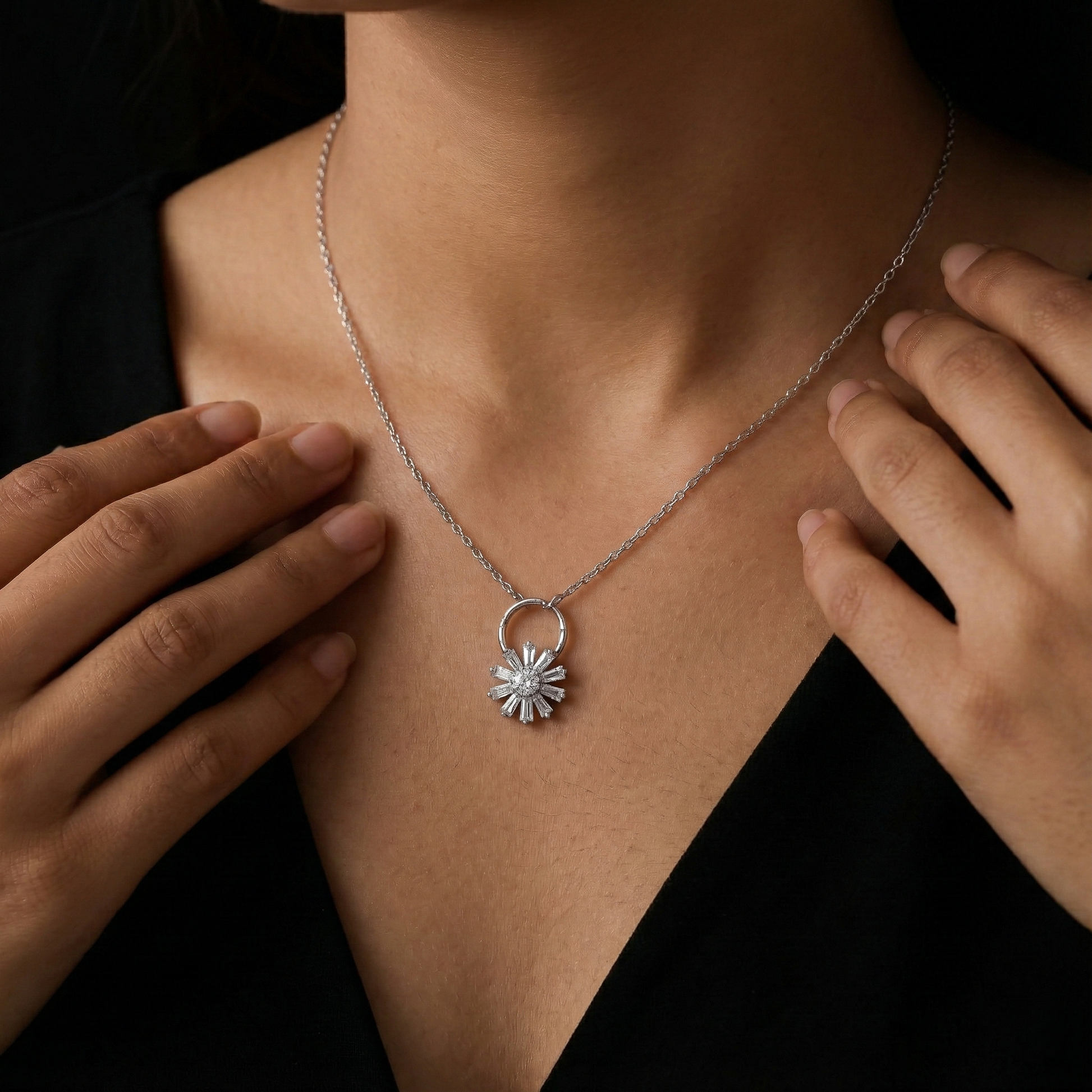Silver necklace with a floral pendant worn by a person against a dark background