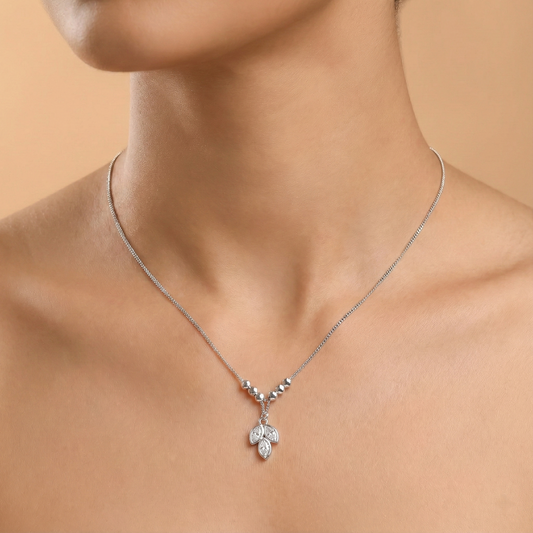 Silver necklace with a pendant on a person against a beige background