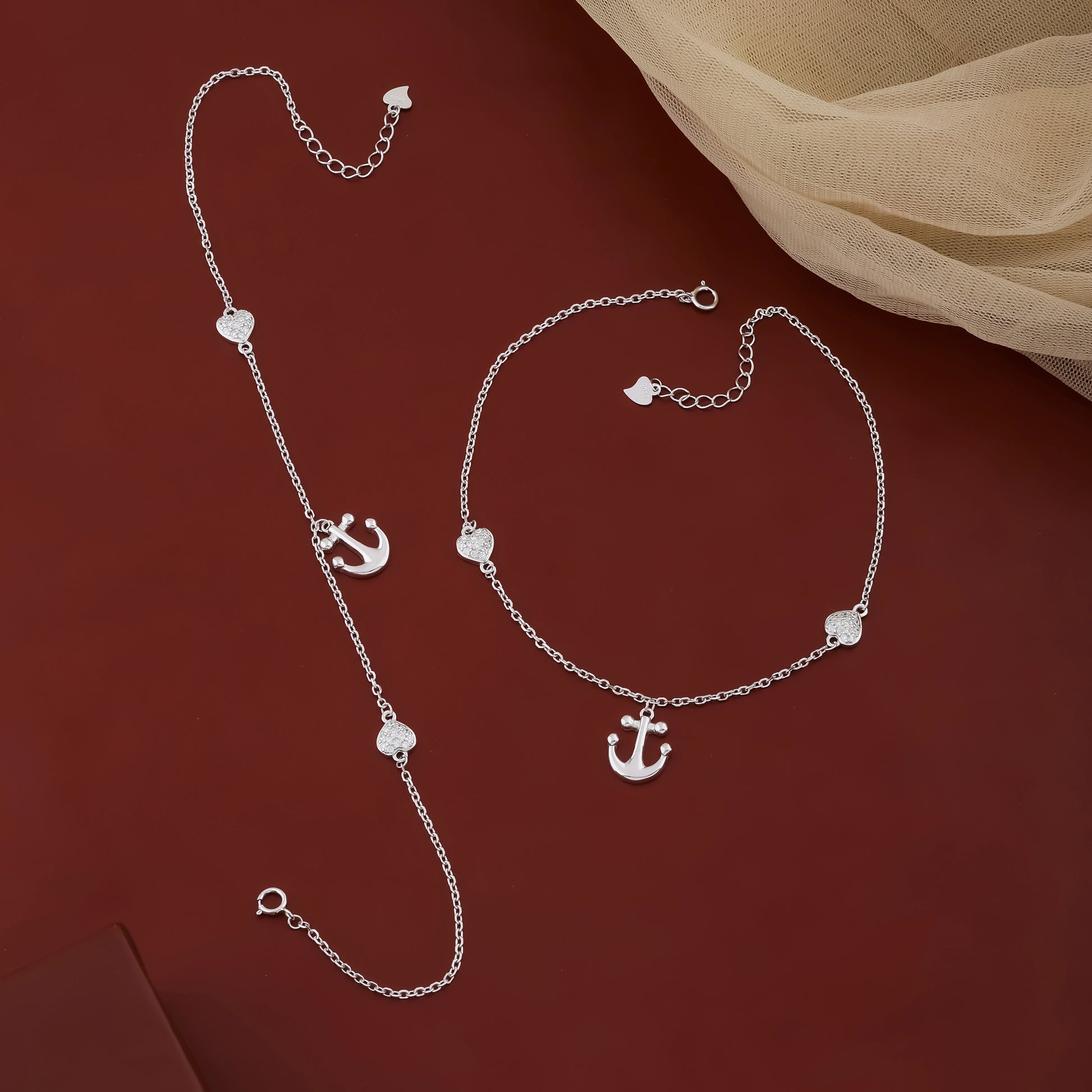 Silver necklace and bracelet set on a red background
