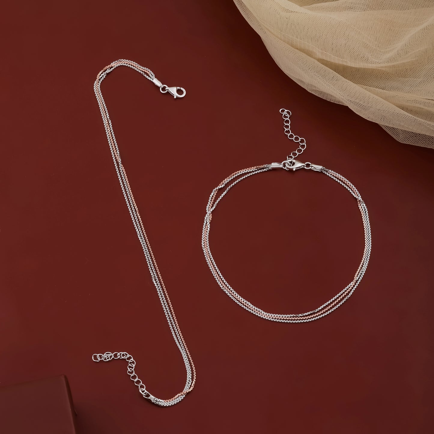 Silver necklace and bracelet set on a red background