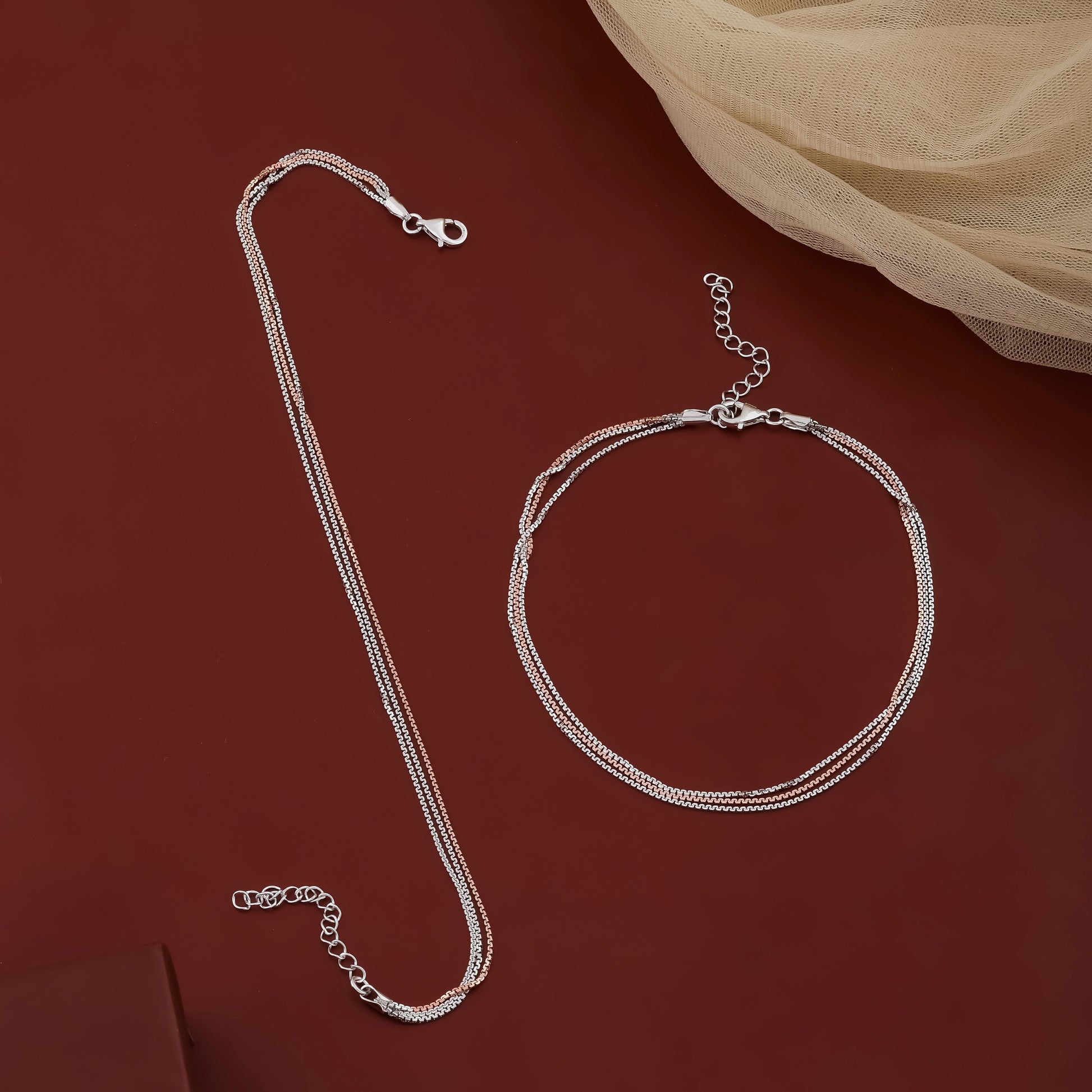 Silver necklace and bracelet set on a red background