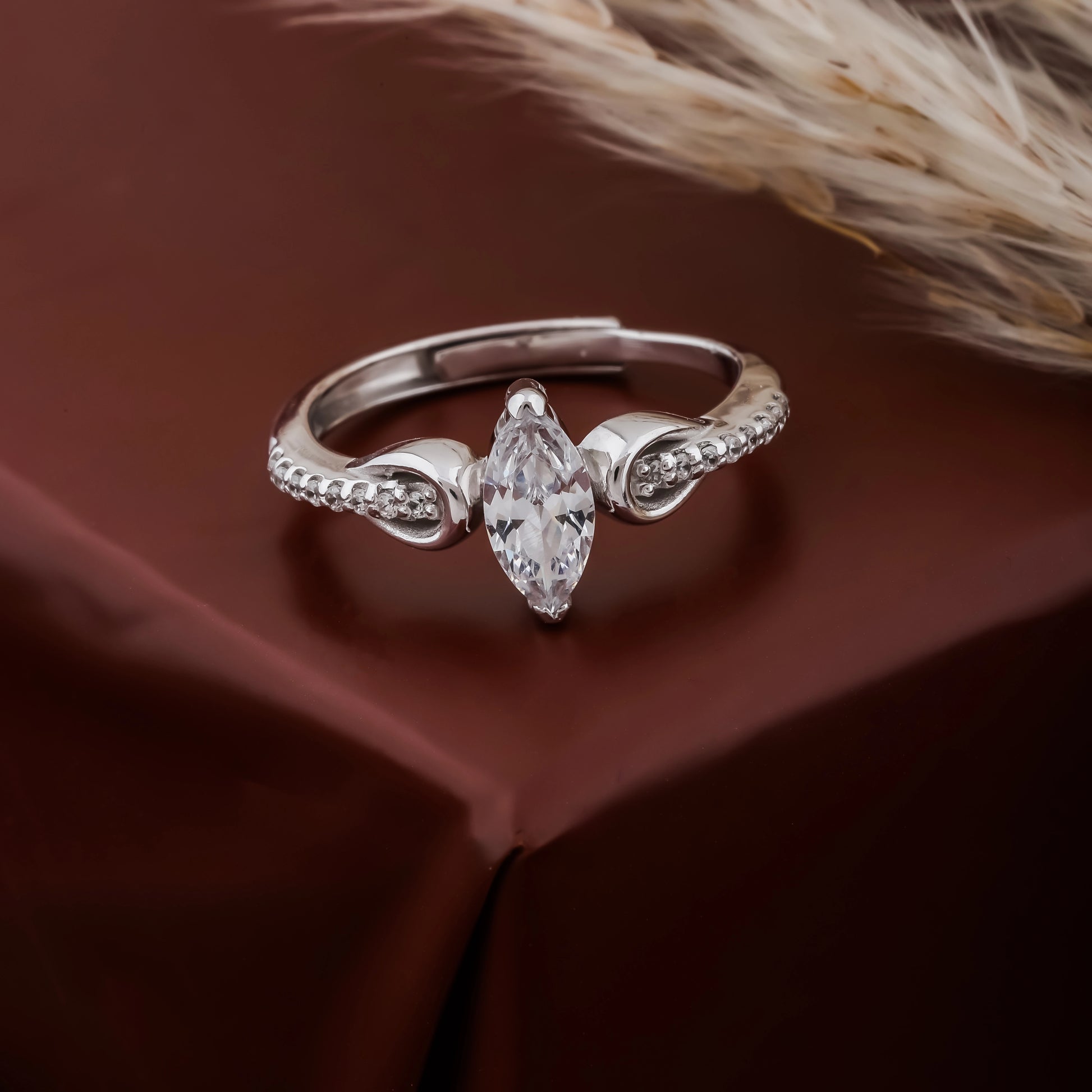 Silver ring with a marquise-shaped diamond on a brown fabric background