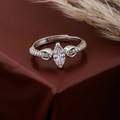 Silver ring with a marquise-shaped diamond on a brown fabric background