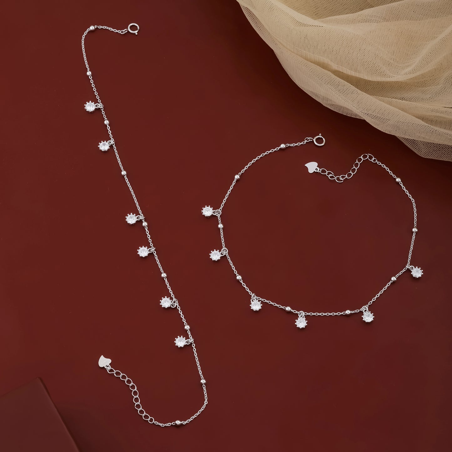 Silver necklace and bracelet set on a red background