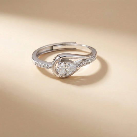 Silver ring with a pear-shaped diamond on a beige background