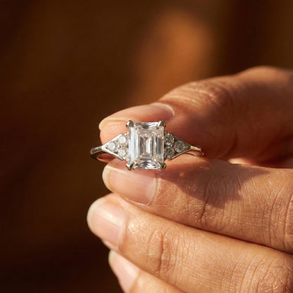 Diamond ring held in a hand with a warm, blurred background
