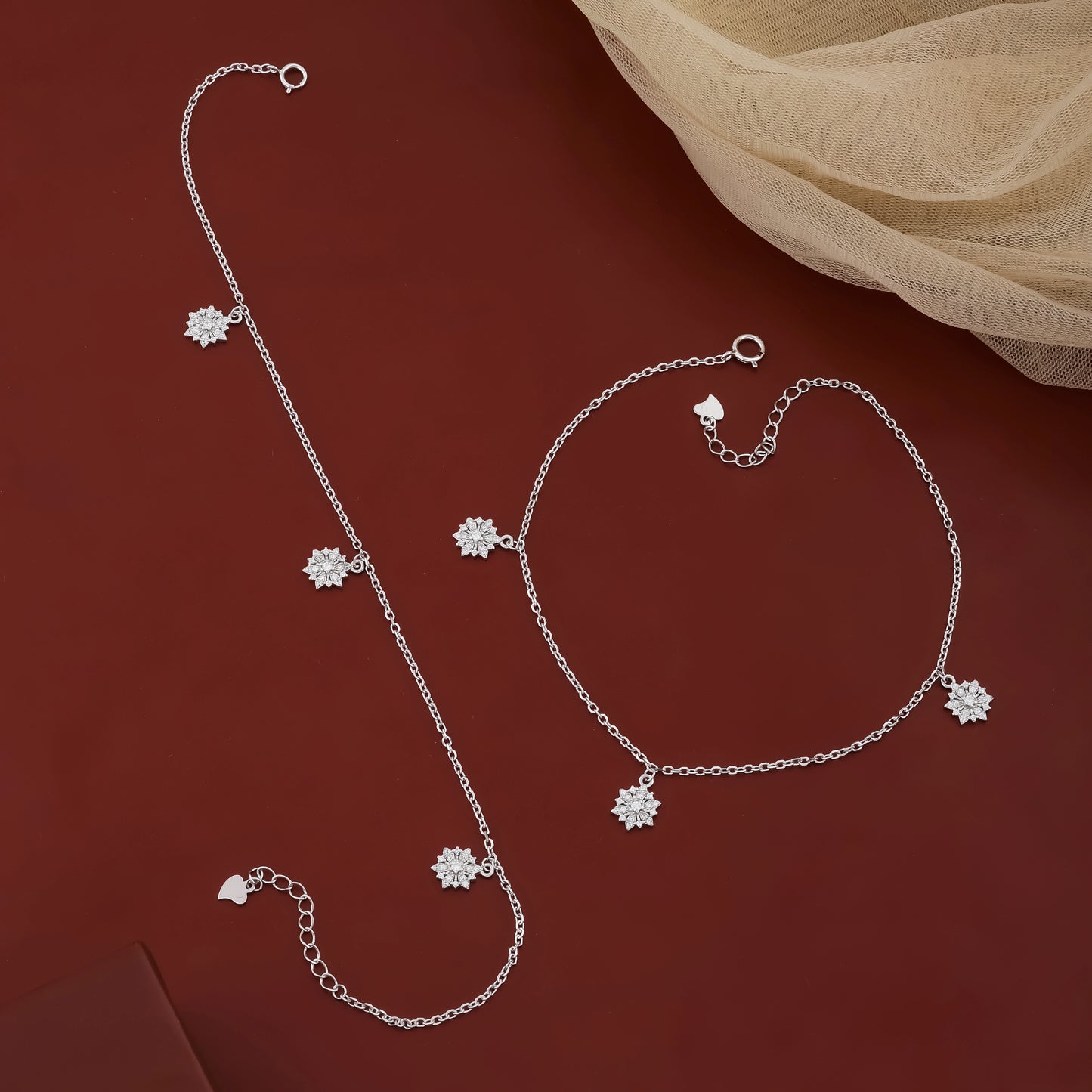 Silver jewelry set with floral charms on a red background