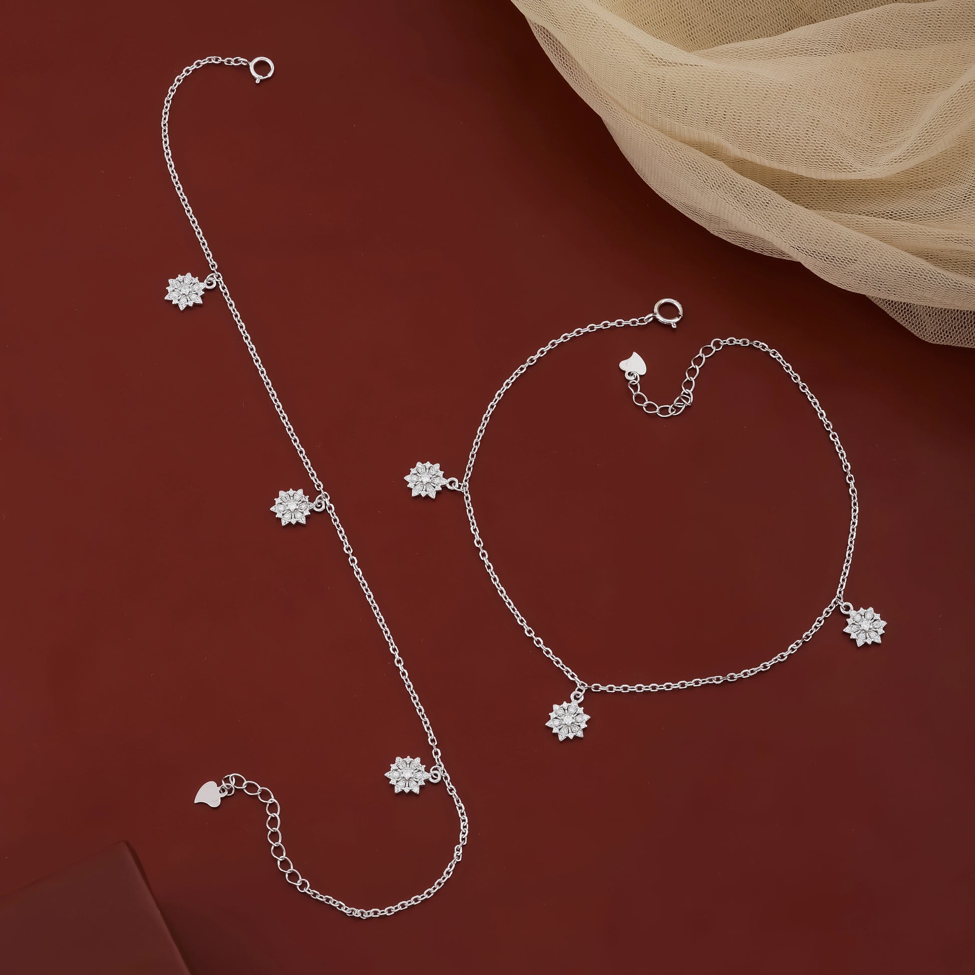 Silver jewelry set with floral charms on a red background