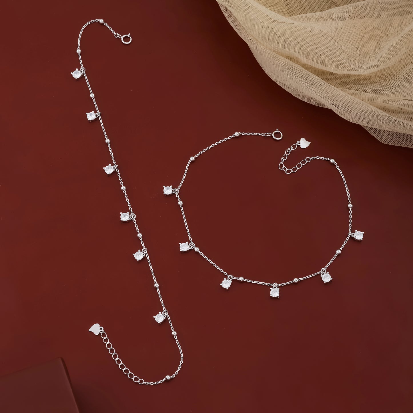 Silver necklace and bracelet set on a red background
