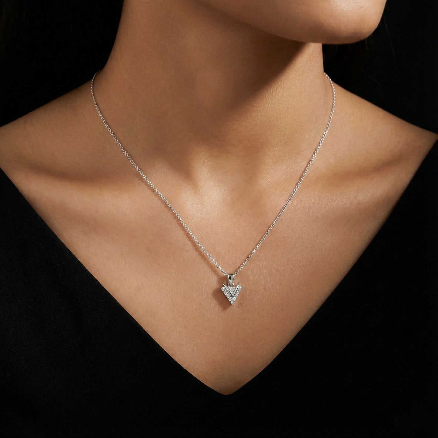 Silver necklace with a heart-shaped pendant on a model against a black background