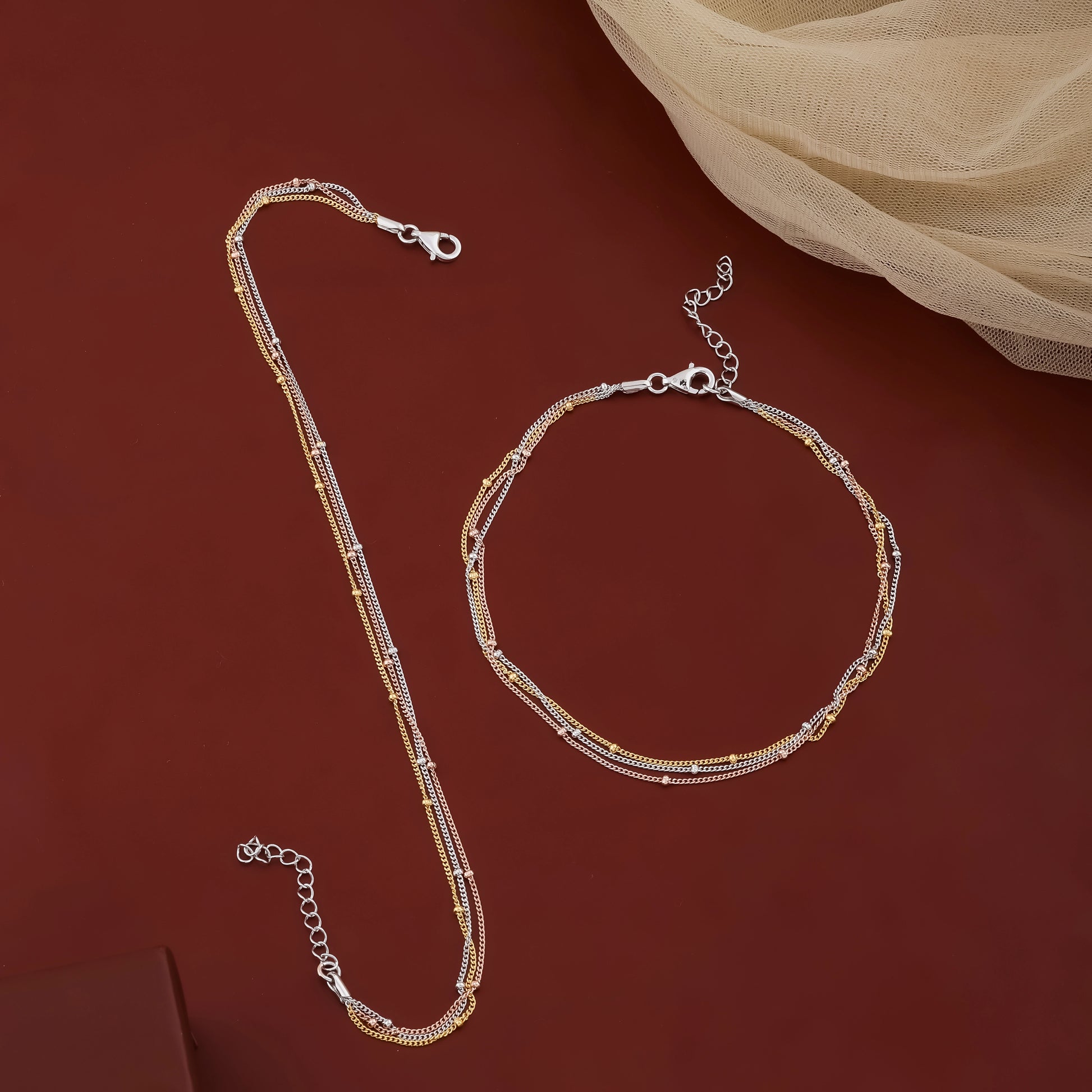 Gold necklace and bracelet set on a red background