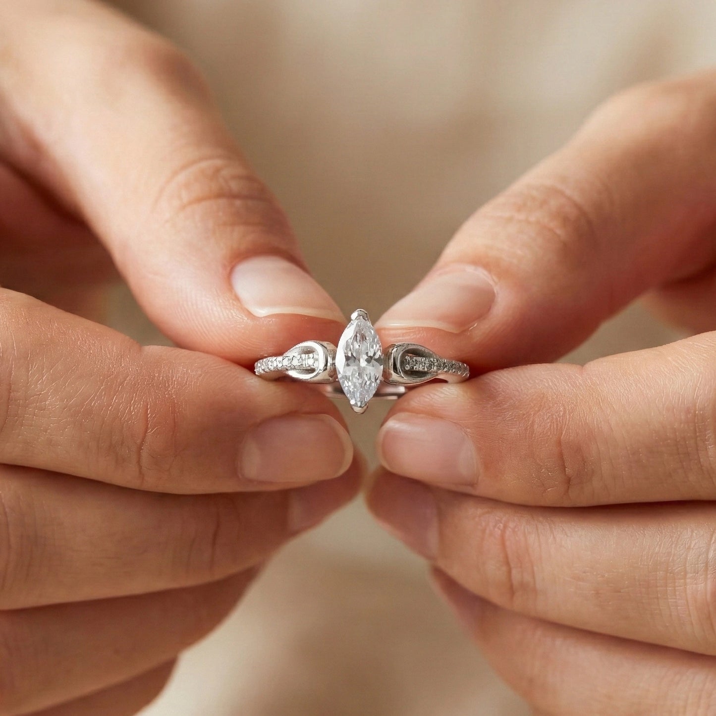 Close-up of hands holding a silver ring with a diamond