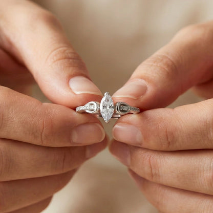 Close-up of hands holding a silver ring with a diamond