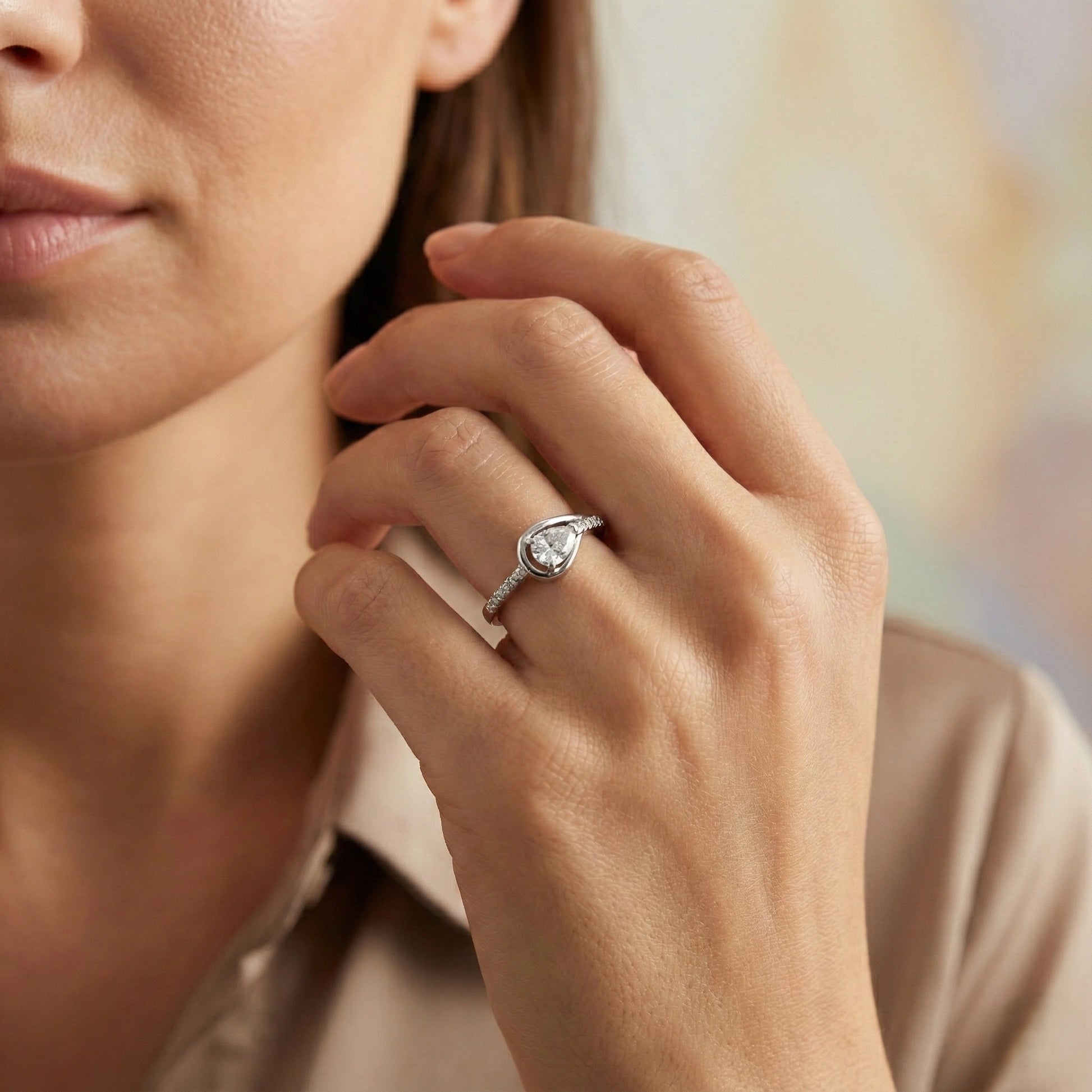 Close-up of a hand wearing a diamond ring with a blurred background