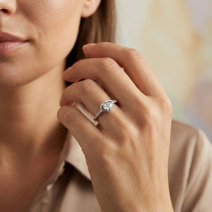 Close-up of a hand wearing a diamond ring with a blurred background