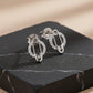 Silver safety pin earrings with clear stones on a dark stone surface