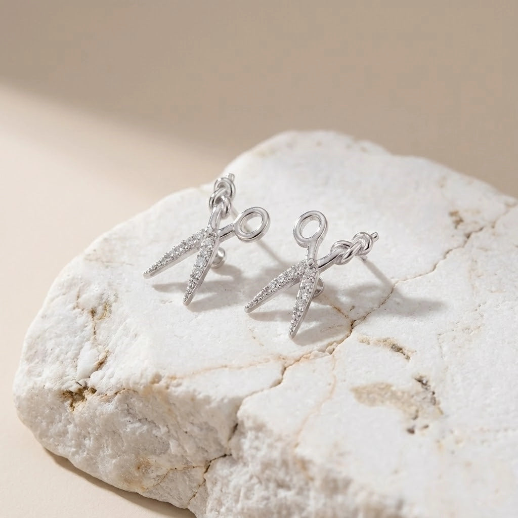 Silver earrings on a textured stone surface