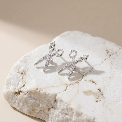 Silver earrings on a textured stone surface