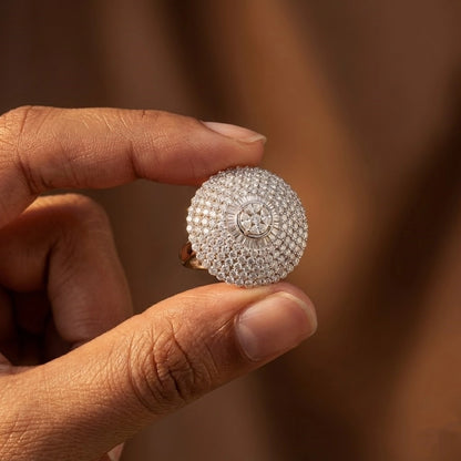 Hand holding a silver ring with intricate design against a blurred background