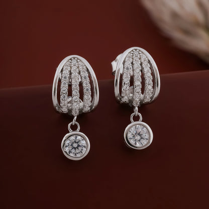 Silver earrings with diamond-like stones on a dark brown background