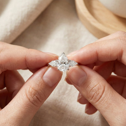 Diamond ring held between two fingers against a neutral background