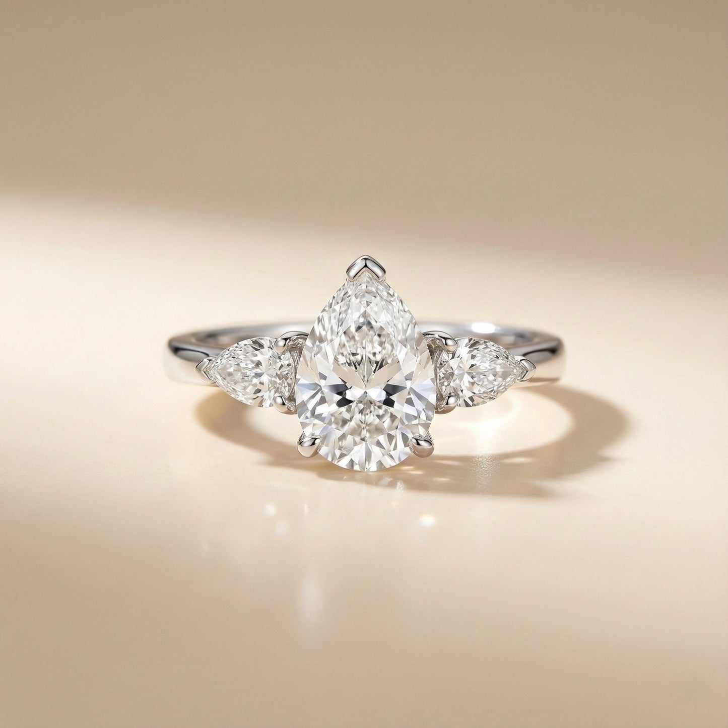 Diamond ring with a pear-shaped center stone on a beige background