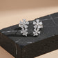 Pair of silver flower-shaped earrings on a dark stone surface