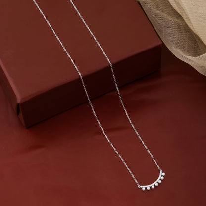 Silver necklace with a delicate pendant on a brown surface