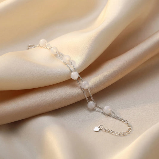 Hand wearing a silver pearl bracelet while holding an open book