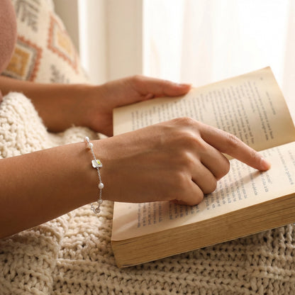 Delicate pearl and butterfly charm bracelet flat lay