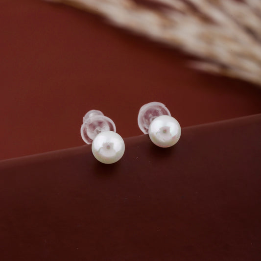 Pair of pearl earrings on a brown surface