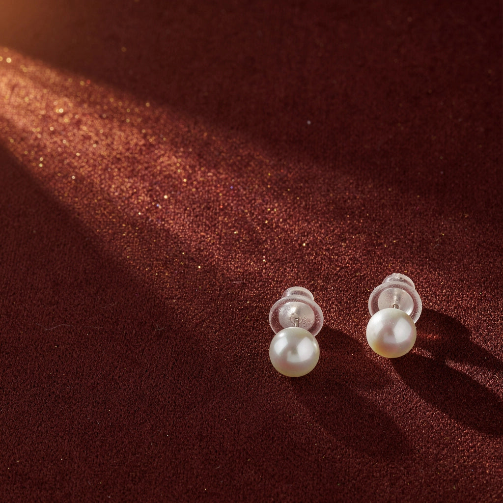 Pearl earrings on a brown textured fabric background