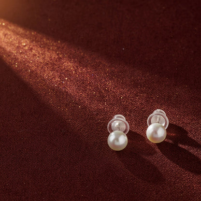 Pearl earrings on a brown textured fabric background