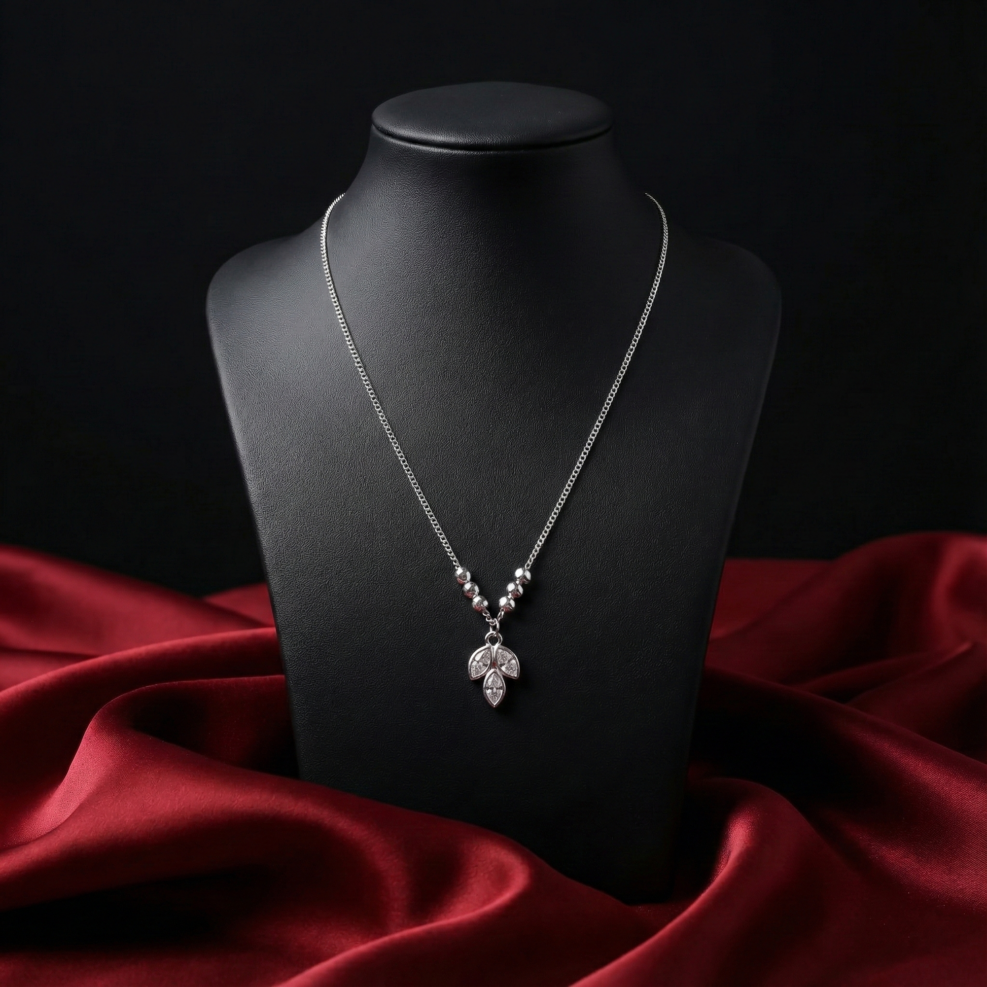 Silver necklace with a pendant on a black mannequin bust against a dark background