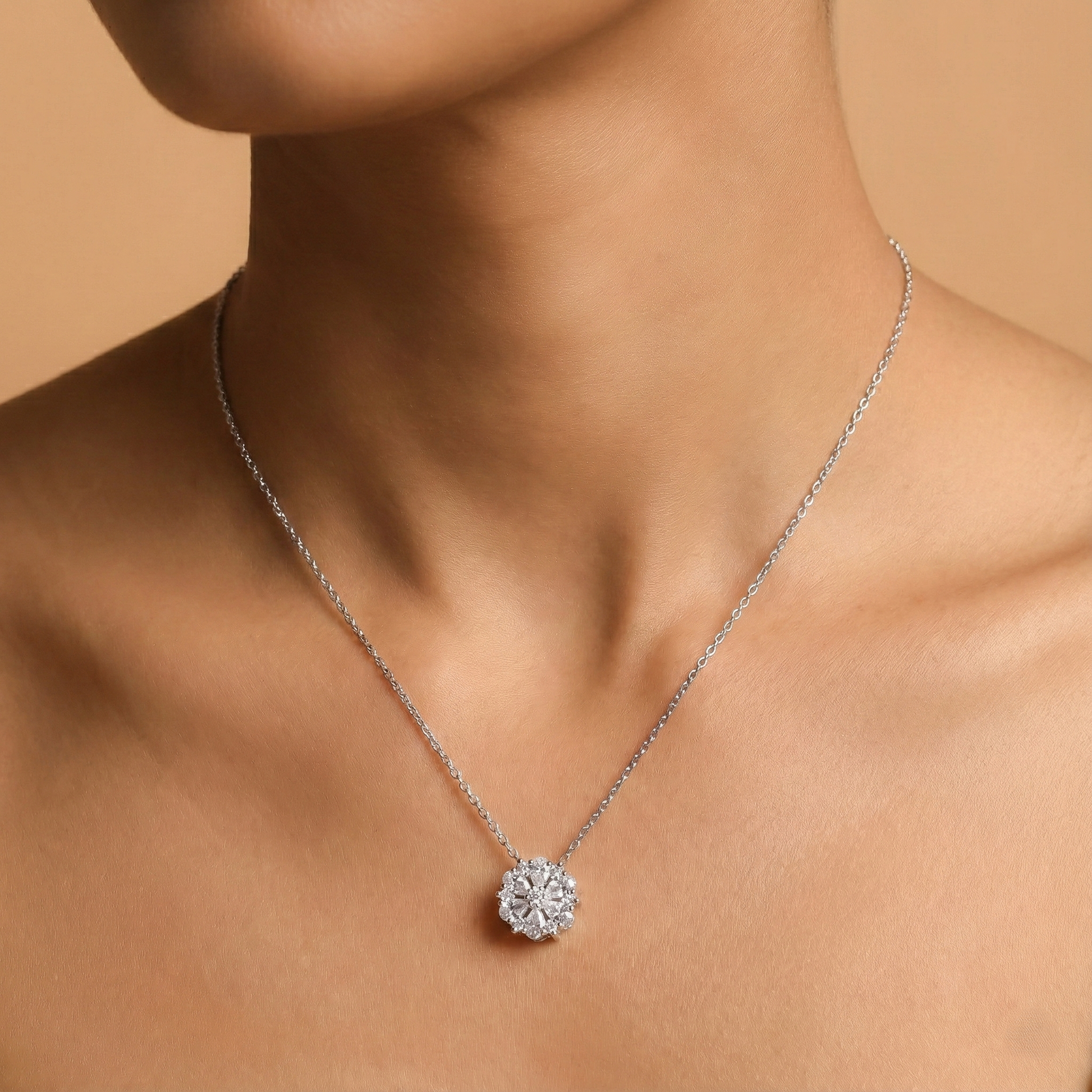 Silver necklace with a diamond pendant on a model against a beige background