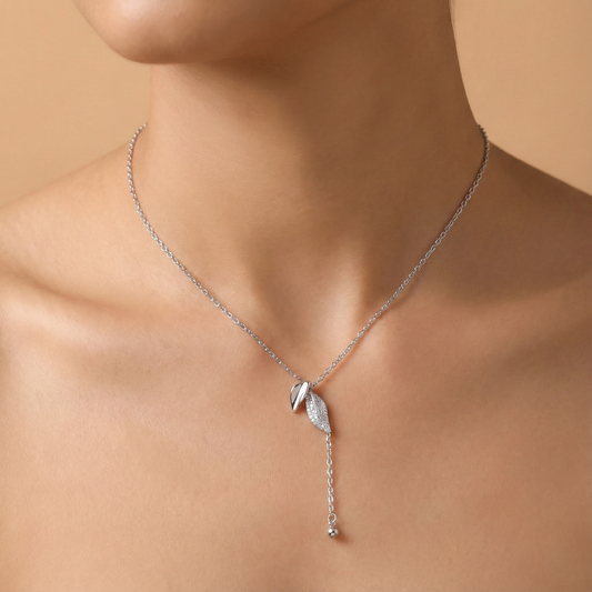 Silver necklace with a pendant on a person against a beige background
