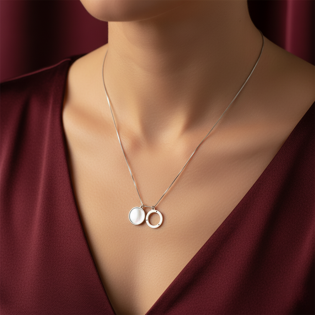 Silver necklace with a pendant on a person wearing a burgundy top.